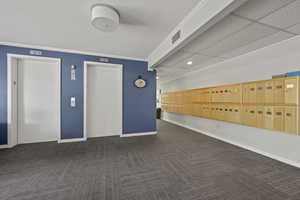 Carpeted empty room with elevator, recessed lighting, mail area, and ornamental molding
