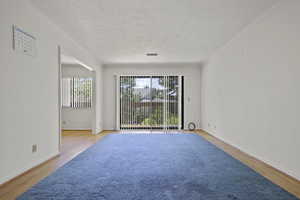 Unfurnished room with plenty of natural light, wood finished floors, crown molding, and a textured ceiling