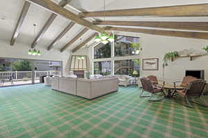 Carpeted living area featuring beam ceiling and high vaulted ceiling