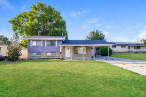 Tri-level home with a carport, brick siding, concrete driveway, and a front yard