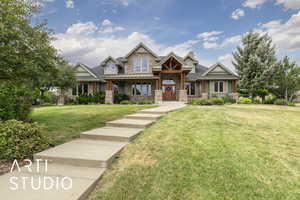 Craftsman-style house featuring stone siding and a front yard