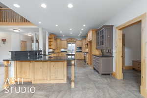 Kitchen with open shelves, a breakfast bar area, glass insert cabinets, recessed lighting, and dark stone countertops