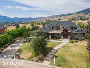 View of front of property featuring stone siding, a mountain view, a front lawn, and a chimney