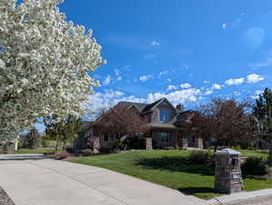 Craftsman-style house with stone siding, a front lawn, a standing seam roof, a metal roof, and concrete driveway