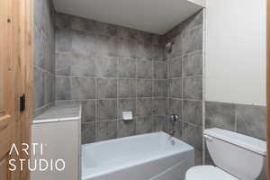 Bathroom featuring tile walls and shower / washtub combination