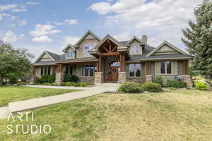 Craftsman-style house featuring stone siding, a front yard, a chimney, and roof with shingles