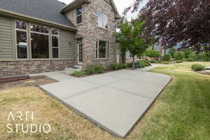 Rear view of property with stone siding, a lawn, and a shingled roof