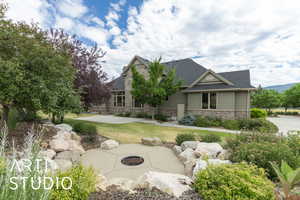 Craftsman-style house featuring stone siding, roof with shingles, a front lawn, and a patio area