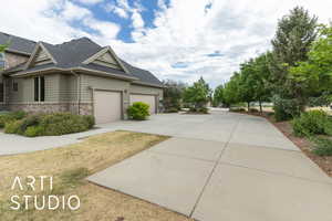 View of home's exterior with an attached garage, driveway, stone siding, and a shingled roof
