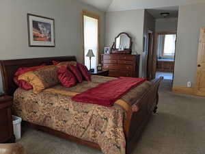 Carpeted bedroom with ensuite bath and vaulted ceiling