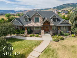 Craftsman inspired home with a mountain view, stone siding, and a front lawn