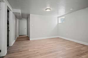 Empty room with a textured ceiling and light wood-style floors