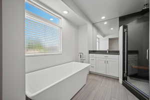Full bath featuring recessed lighting, a shower stall, a freestanding tub, and vanity
