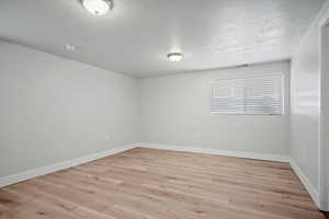 Empty room with a textured ceiling and light wood-style flooring