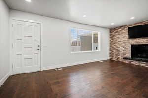 Unfurnished living room with recessed lighting, hardwood / wood-style floors, brick wall, and a fireplace