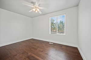 Unfurnished room featuring dark wood finished floors and ceiling fan