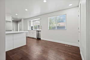 Kitchen featuring dark wood-type flooring, light countertops, recessed lighting, white cabinetry, and stainless steel appliances