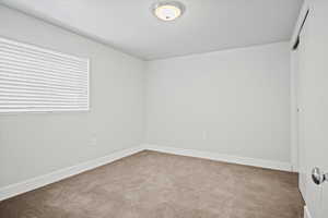 Empty room featuring carpet and baseboards
