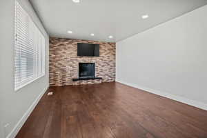 Unfurnished living room with wood-type flooring, recessed lighting, and a brick fireplace