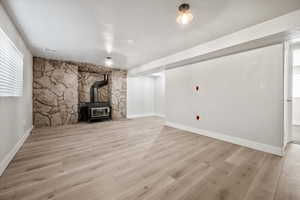 Unfurnished living room featuring healthy amount of natural light, a wood stove, and wood finished floors