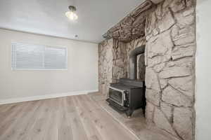Unfurnished living room featuring a wood stove, wood finished floors, and a textured ceiling