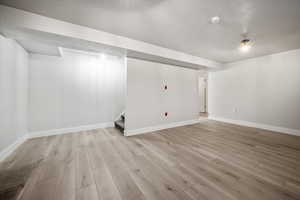 Finished below grade area with light wood-style flooring and stairs