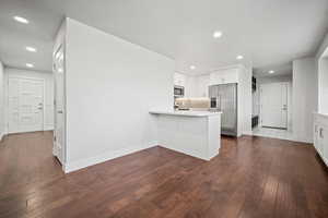 Kitchen featuring recessed lighting, appliances with stainless steel finishes, a peninsula, dark wood-type flooring, and light countertops