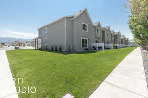 View of property exterior featuring a residential view, stucco siding, a yard, and a mountain view
