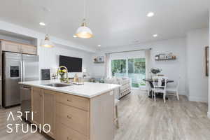 Kitchen featuring light brown cabinets, appliances with stainless steel finishes, light wood finished floors, light countertops, and recessed lighting