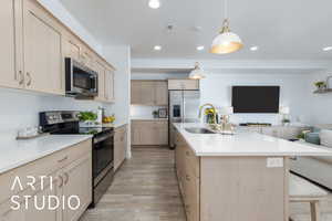 Kitchen with light brown cabinets, stainless steel appliances, open floor plan, light wood-style flooring, and recessed lighting