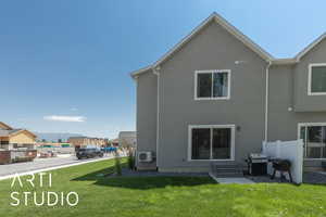 Rear view of house with a yard, stucco siding, entry steps, and a mountain view
