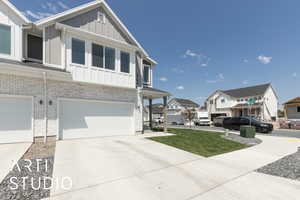 View of front facade featuring a residential view, board and batten siding, brick siding, concrete driveway, and an attached garage