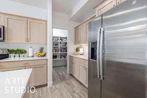 Kitchen featuring appliances with stainless steel finishes, light countertops, light wood finished floors, and light brown cabinets