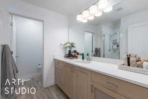 Bathroom featuring vanity, wood finished floors, and a stall shower