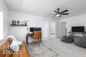 Carpeted office space with a ceiling fan and baseboards