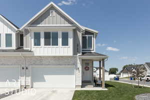View of front of home featuring board and batten siding, concrete driveway, a garage, and a front lawn