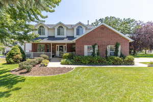 View of front of house with brick siding, a front yard, and a porch