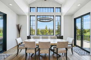 Dining room with wood finished floors, lofted ceiling, and recessed lighting