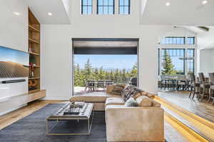 Living room featuring hardwood / wood-style floors, a high ceiling, built in shelves, and recessed lighting
