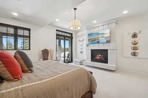 Carpeted bedroom with recessed lighting and a glass covered fireplace
