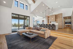 Living room featuring high vaulted ceiling, light wood-style floors, plenty of natural light, and recessed lighting
