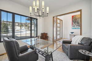 Living area with a chandelier, healthy amount of natural light, wood finished floors, and french doors