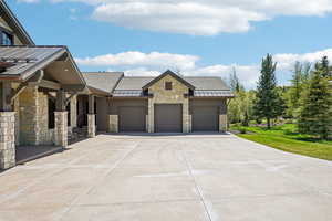 View of front facade with a garage, stone siding, and concrete driveway