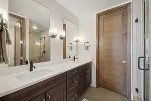 Full bath featuring double vanity, a stall shower, and tile patterned flooring
