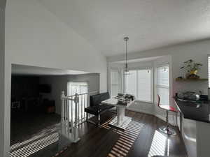 Dining space with wood finished floors, a textured ceiling, and vaulted ceiling