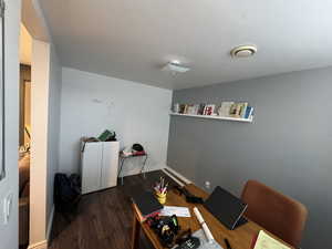 Home office featuring dark wood-type flooring and baseboards