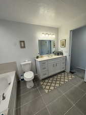 Full bathroom featuring vanity, a garden tub, tile patterned floors, and a textured ceiling