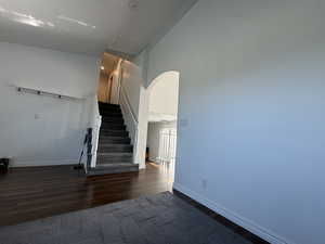 Staircase with wood finished floors, arched walkways, and a high ceiling