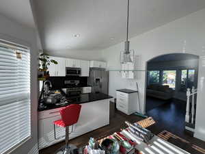 Kitchen featuring dark countertops, stainless steel appliances, white cabinetry, a textured ceiling, and a peninsula