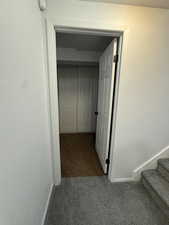 Hallway with dark carpet and stairs